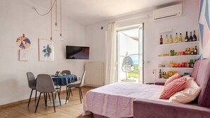 A bedroom with a bed, a desk, chairs, a TV, and a shelf with bottles. - Boutique Apartment Eleganza (Chiusi Scalo)