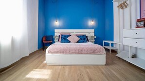 A bedroom with a white bed, blue walls, and a wooden floor. - Boutique Apartment Eleganza (Chiusi Scalo)