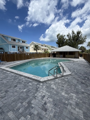 A swimming pool with a wooden deck, a covered seating area, and a fenced property. - 2 Bedroom condo directly across the street from the beach! (Placida)