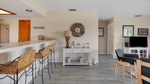 Una cocina moderna con encimera blanca, taburetes de bar y un espejo fijado a la pared.