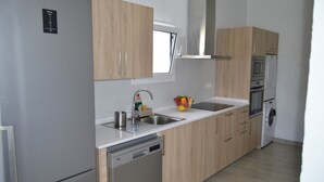 A modern kitchen with wooden cabinets, stainless steel appliances, and a built-in dishwasher. - House overlooking the volcano with garden, solarium, terrace and barbecue (Ye)