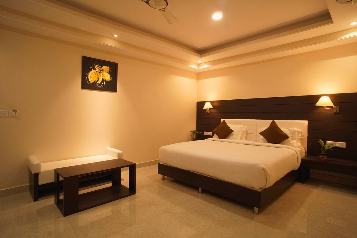 Een moderne slaapkamer met een groot bed, nachtkastjes, een bankje en een wandlamp.