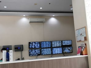 Reception area with a digital display and cash register, featuring a bulletin board and brochures.