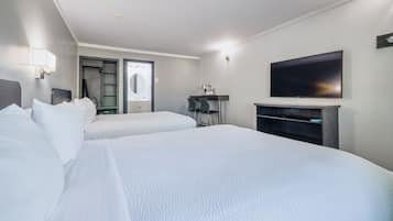 Ein Hotelzimmer mit zwei Betten, einem Fernseher und einem Schreibtisch.