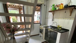 A kitchen with a built-in stove, a sink, and a window overlooking a garden. - Mareou (Angra dos Reis)