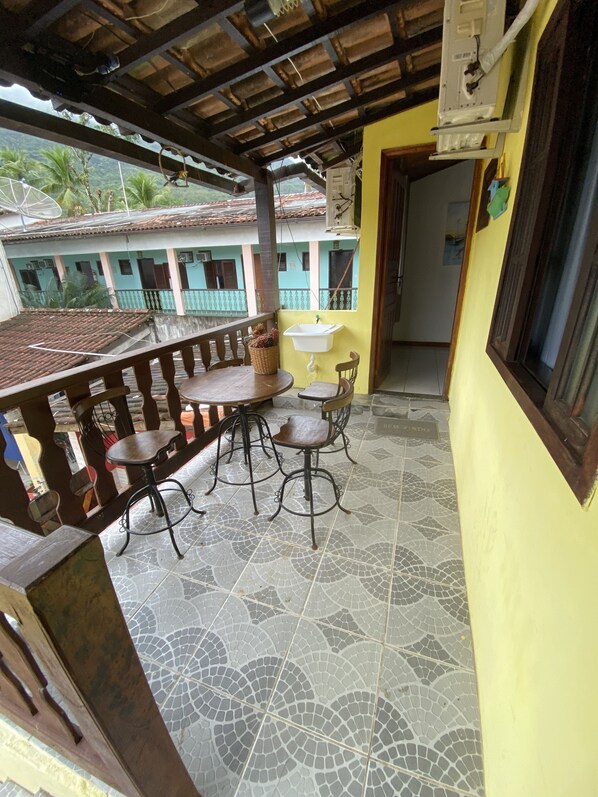A covered outdoor patio with a table and chairs, a sink, and a view of buildings in the background.