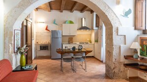 Une cuisine rustique avec une arche, une table à manger avec des chaises et un canapé.