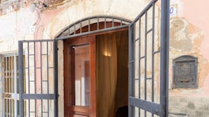 Un portail en arc surmonté d’une porte en bois, une grille en métal et un mur de pierre orné d’un numéro.