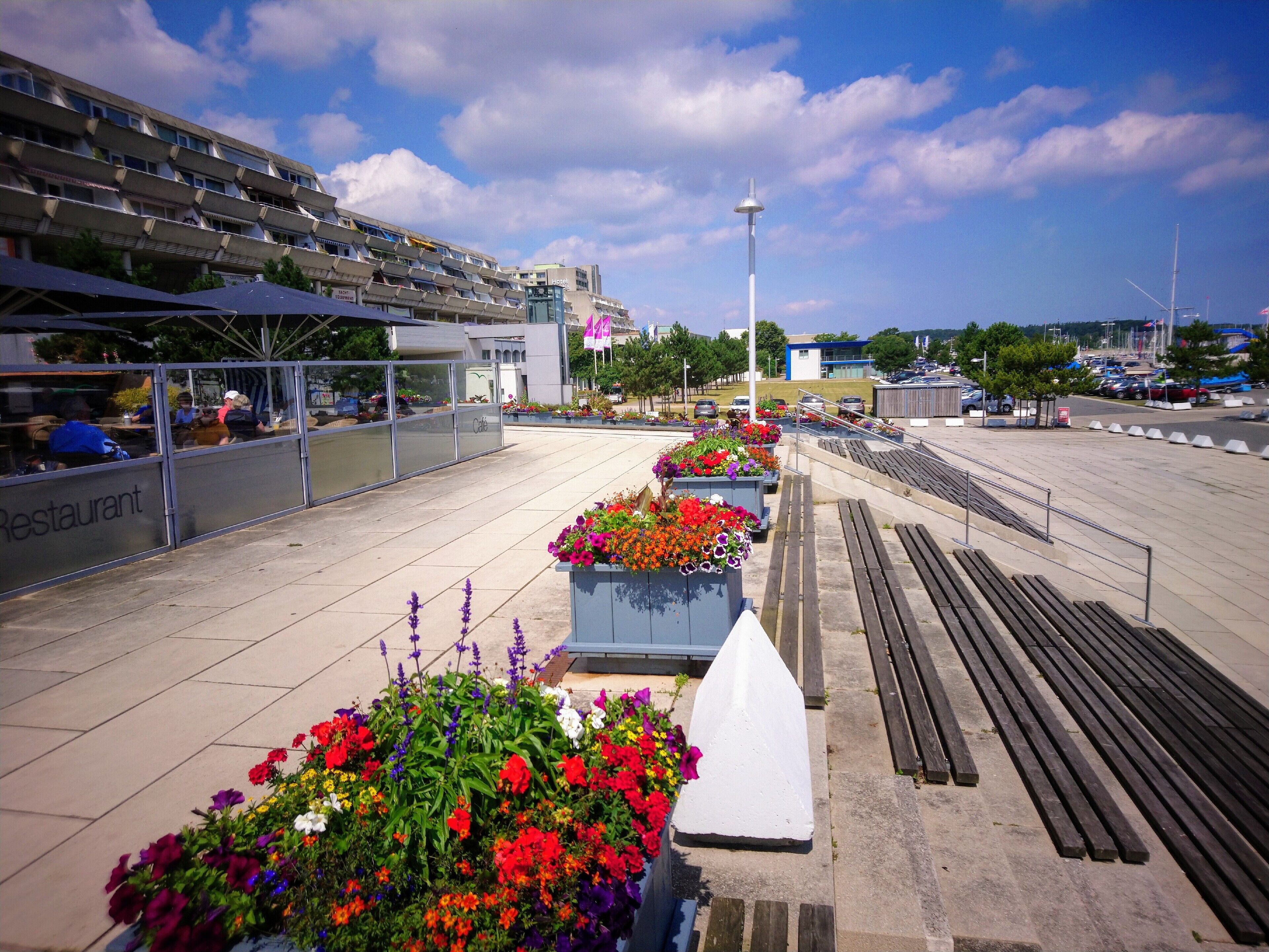 A rooftop terrace with outdoor seating, a modern building with a glass facade, and a clear sky.
