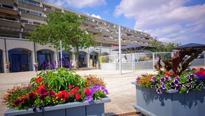 A modern building with balconies and a courtyard with flower planters.