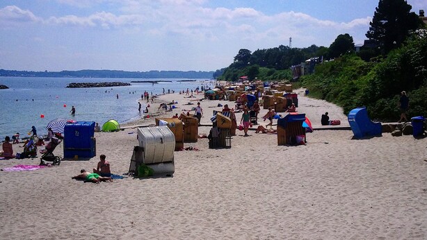 A beach with people, tents, and a sandy shore.