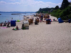 Une plage avec des gens, des tentes et un rivage sablonneux.