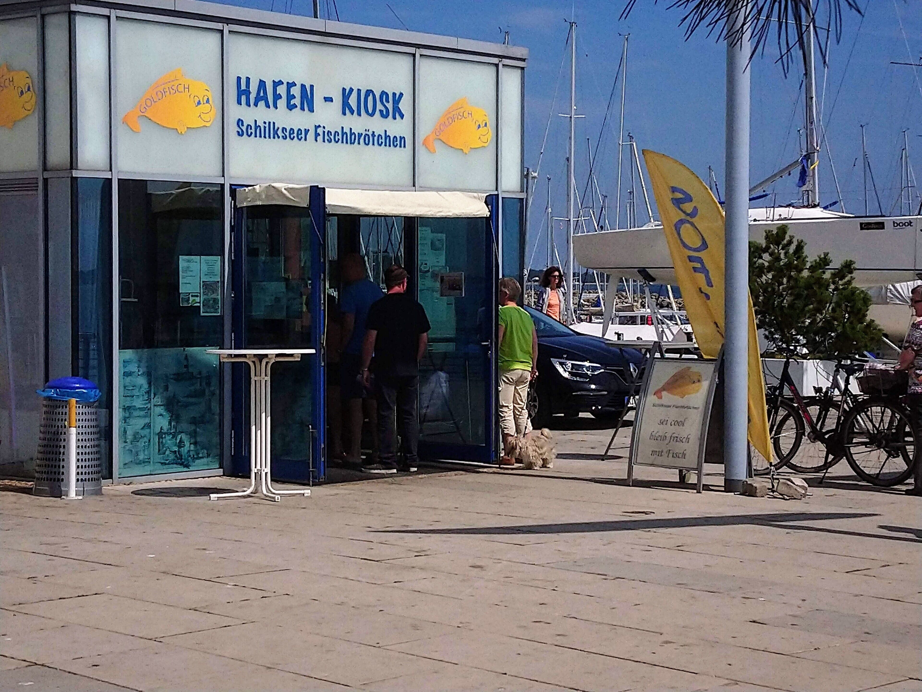 Un quiosco llamado 'Hafen - Kiosk' con un cartel que muestra un pez sonriente.