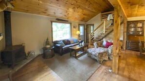 Ein gemütliches Wohnzimmer mit Kamin, einer Couch, einem Couchtisch und einer Treppe.