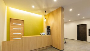 Una recepción con detalles de madera, una pared de acento amarilla y una lámpara moderna.