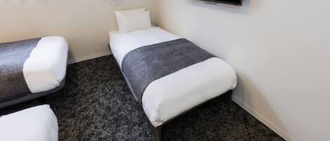 A hotel room with two single beds, a flat-screen TV, and a window with curtains.