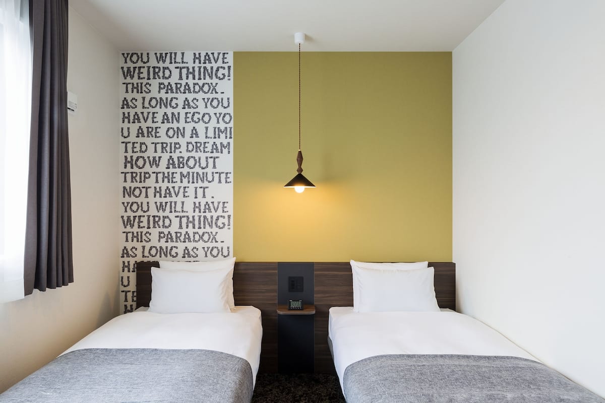 A hotel room with two beds, a nightstand, and a wall with motivational text.