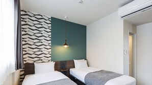Habitación de hotel con dos camas, un papel tapiz estampado, una lámpara colgante y un equipo de aire acondicionado.