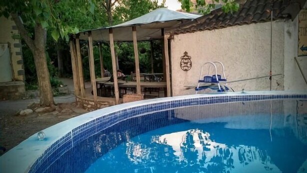 A swimming pool with a tiled edge, a covered seating area, and a ladder leading into the pool. - Casa Baltasar, ideal for families and friends, with garden and barbecue. (Isábena)