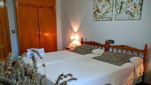 A bedroom with a wooden bed, white bedding, a nightstand with a lamp, and two wall art pieces. - Casa Baltasar, ideal for families and friends, with garden and barbecue. (Isábena)