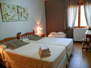 A room with two beds, a desk, and a window with curtains. - Casa Baltasar, ideal for families and friends, with garden and barbecue. (Isábena)