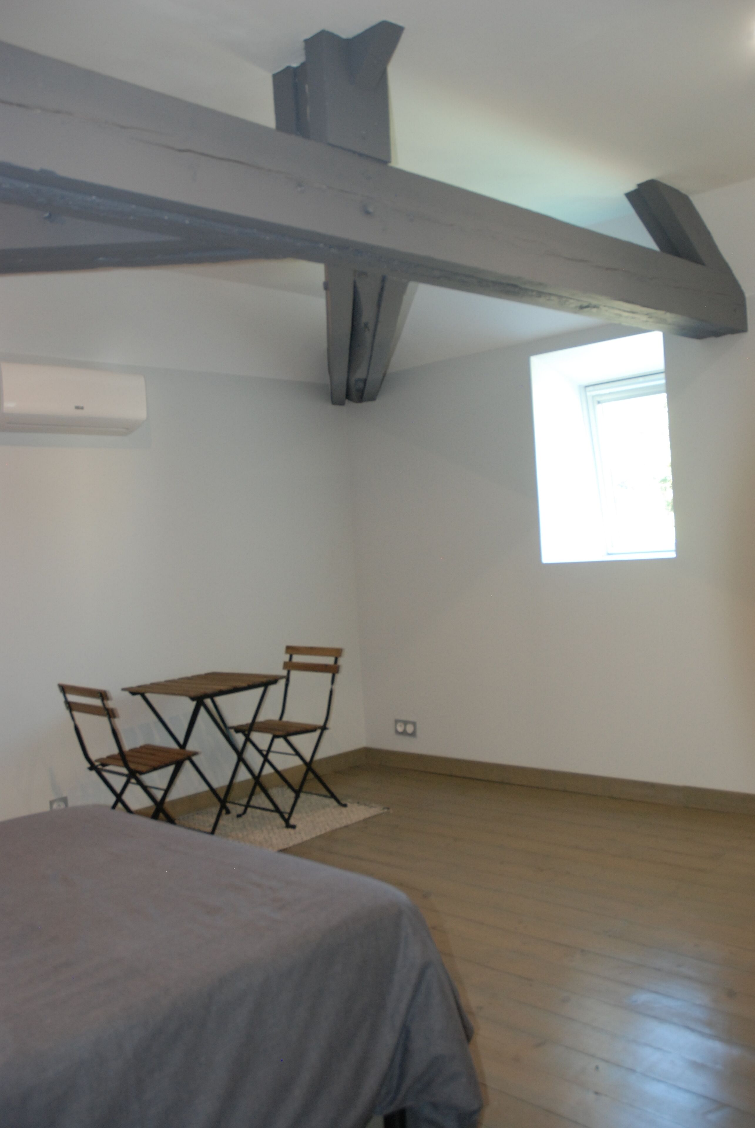 A high ceiling with a skylight, a wooden beam structure, and a geometric wall art piece.