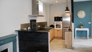 Una cocina moderna con una isla negra, electrodomésticos de acero inoxidable, armarios de madera y una pared de acento azul.