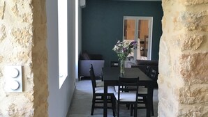 Un estrecho pasillo con paredes de piedra, techo de madera y un comedor con mesa y sillas.