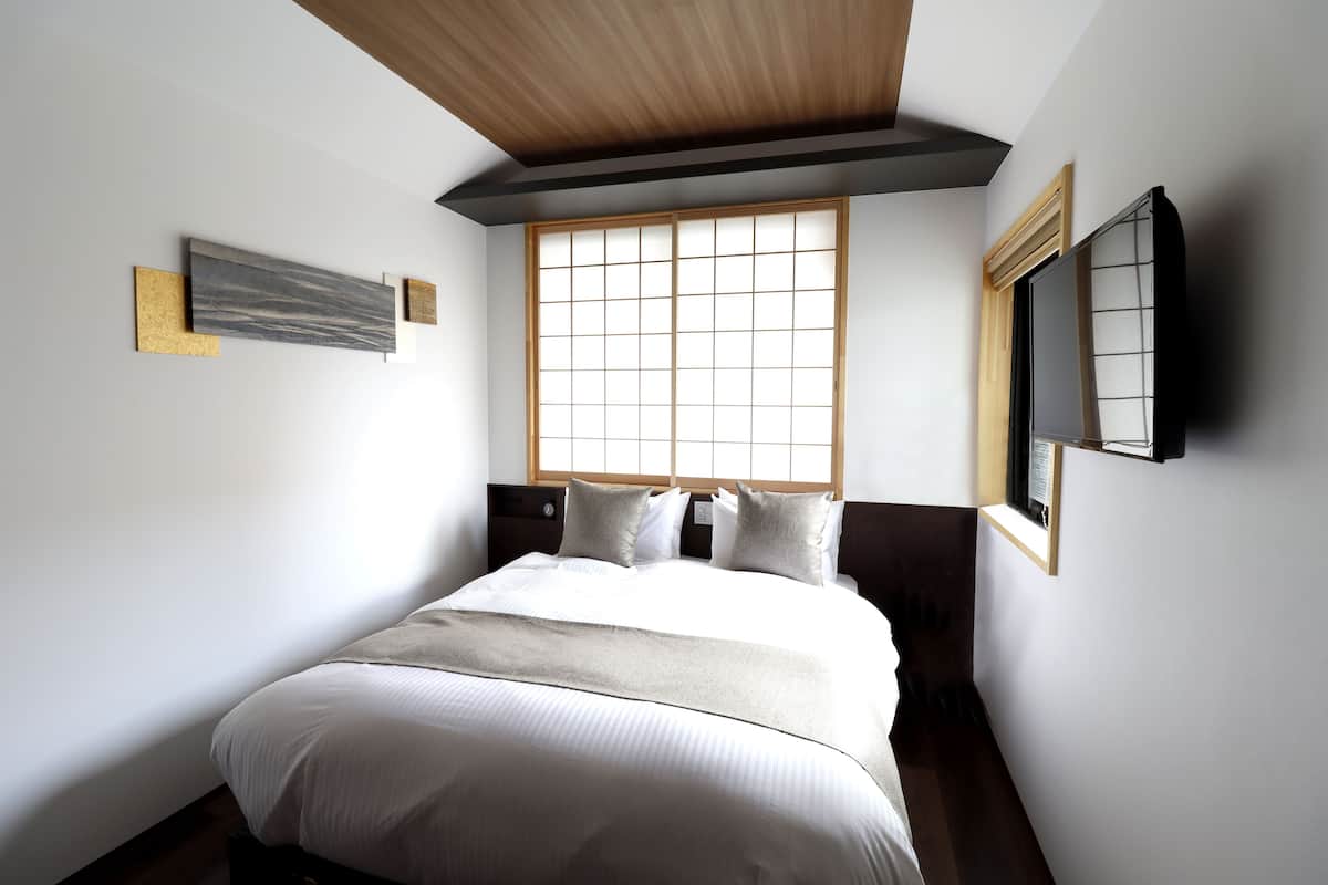 Ein Schlafzimmer mit einem großen Bett, einem Fenster mit Blick und einem wandmontierten Fernseher.