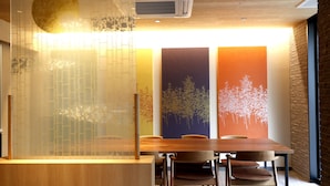 A modern interior with a wooden reception desk, a seating area with chairs, and a wall with vertical panels. - Stay SAKURA Kyoto SUZAKU OJI (Kyoto)
