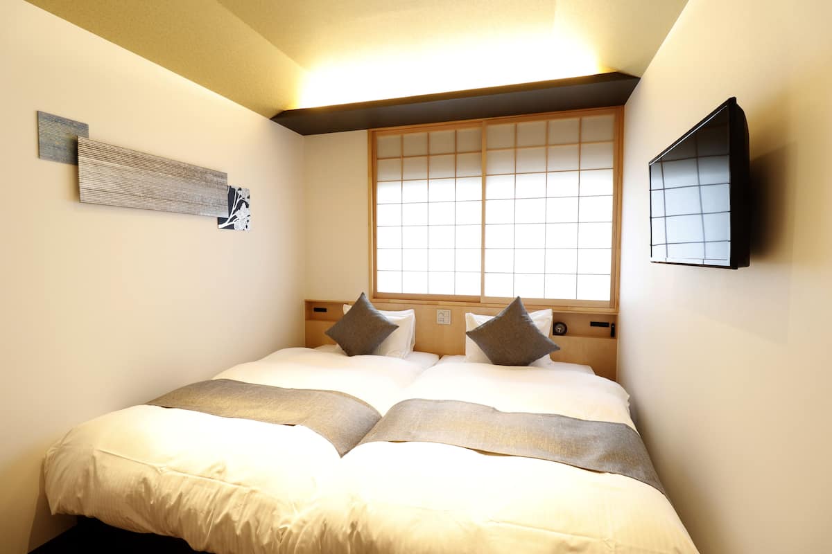 Ein Hotelzimmer mit einem großen Bett, einem Fenster mit Blick und einem an der Wand befestigten Fernseher.