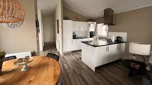 Et moderne køkken med hvide skabe, en central ø og et spiseområde med et træbord.