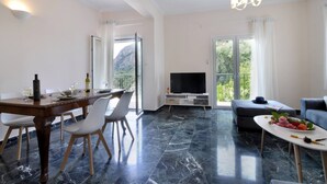 Una sala de estar moderna con comedor, televisor de pantalla plana, sofá y balcón con vista a la montaña.