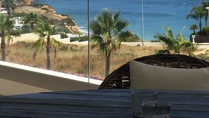A balcony with a view of the ocean, palm trees, and a wooden table with glasses. - Stunning ocean view, Prime location, Exclusive design (Lagos)