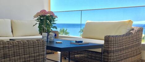 A balcony with wicker furniture, a table, and a vase of flowers.