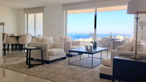 A modern living room with a large window, white sofas, a coffee table, and a dining area. - Stunning ocean view, Prime location, Exclusive design (Lagos)