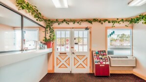 A room with a patterned carpet, a double door with a window, a vending machine, and a potted plant. - OYO Hotel Durham West Hills (Durham)