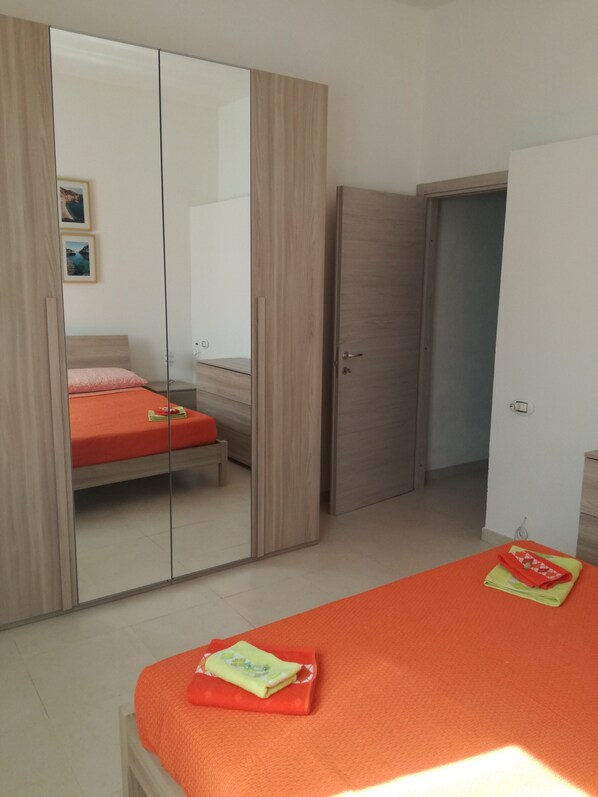 A bedroom with a bed, a wardrobe, and a mirror.