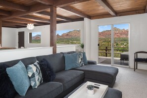 Relax in this stylish living space with a sofa, potted plant, and scenic views of red rock formations.