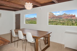 Enjoy meals in this spacious dining area with a wooden table and four chairs, offering views of the surrounding mountains.