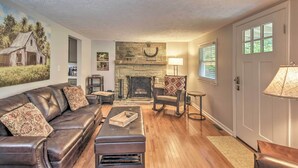 A living room with a fireplace, leather sofa, and a dining area. - Blowing Rock Home: 1 Block to Downtown! (Blowing Rock)
