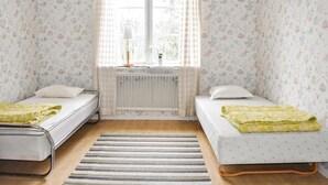 A room with two single beds, a radiator, a window with curtains, and a striped rug. - 2 bedroom gorgeous home in Gunnarskog (Gunnarskog)