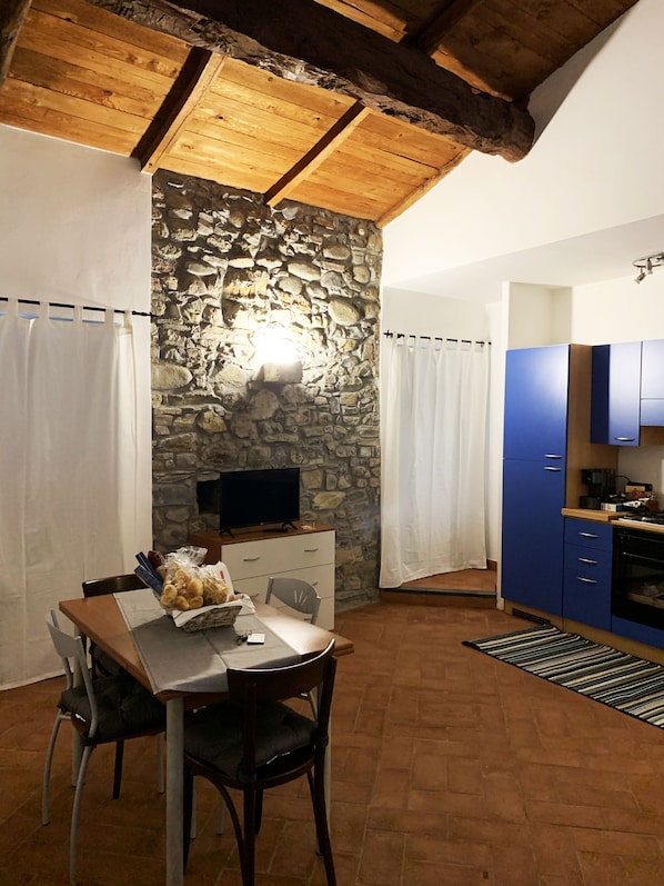 A rustic kitchen with stone walls, a wooden ceiling, and blue cabinets.