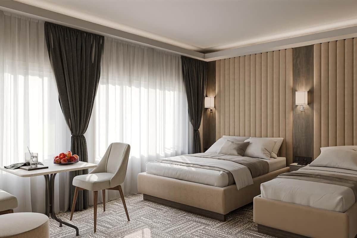 Ein Hotelzimmer mit zwei Betten, einem Schreibtisch, einem Stuhl und einem Tisch mit Früchten.