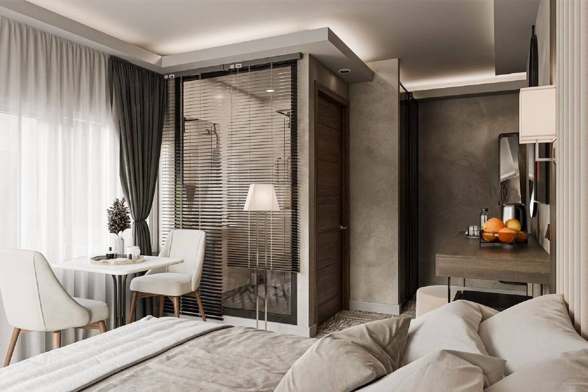 Ein modernes Hotelzimmer mit Bett, Schreibtisch, Stuhl und einem großen Fenster mit Vorhängen.