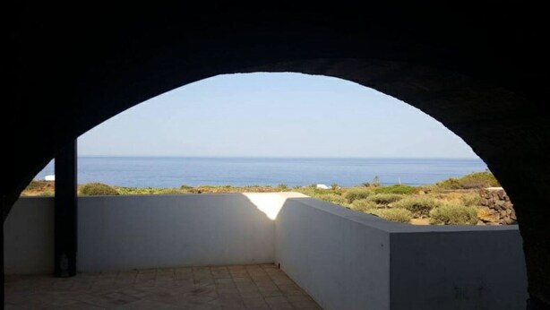 Une pièce offrant une vue sur la mer, visible à travers une ouverture en arc de cercle.
