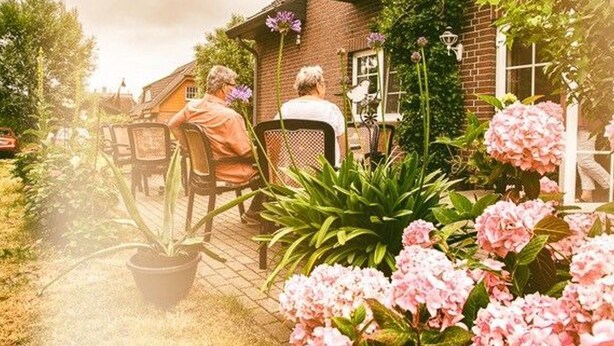 Un cadre résidentiel comprenant une maison en briques, un espace extérieur aménagé pour s’asseoir et des plantes en pot.