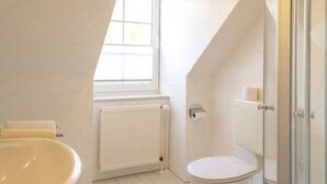 Une salle de bain avec une baignoire, des toilettes et une fenêtre.