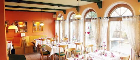 Un interior de restaurante con varias mesas, sillas y una barra.