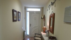 A hallway with a white door, a radiator, a chair, a table with a lamp, and a mirror on the wall. - Large house with private garden / pool at 1500 meters from the sea (Playa de Aro) (Calonge)